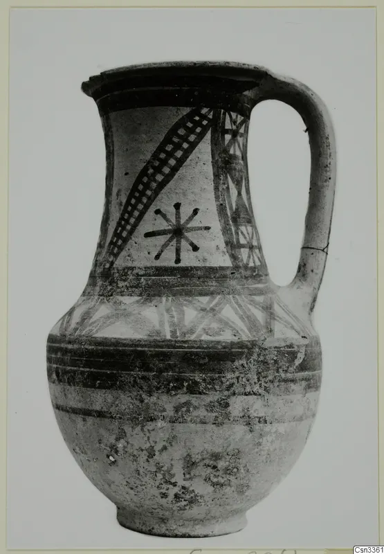 Painted pottery jug with a single loop handle, black bands and a star-like motif on a light ground.