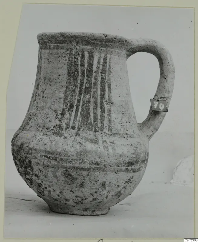Wheel-made pottery jug with a single loop handle and painted vertical stripes on the body.