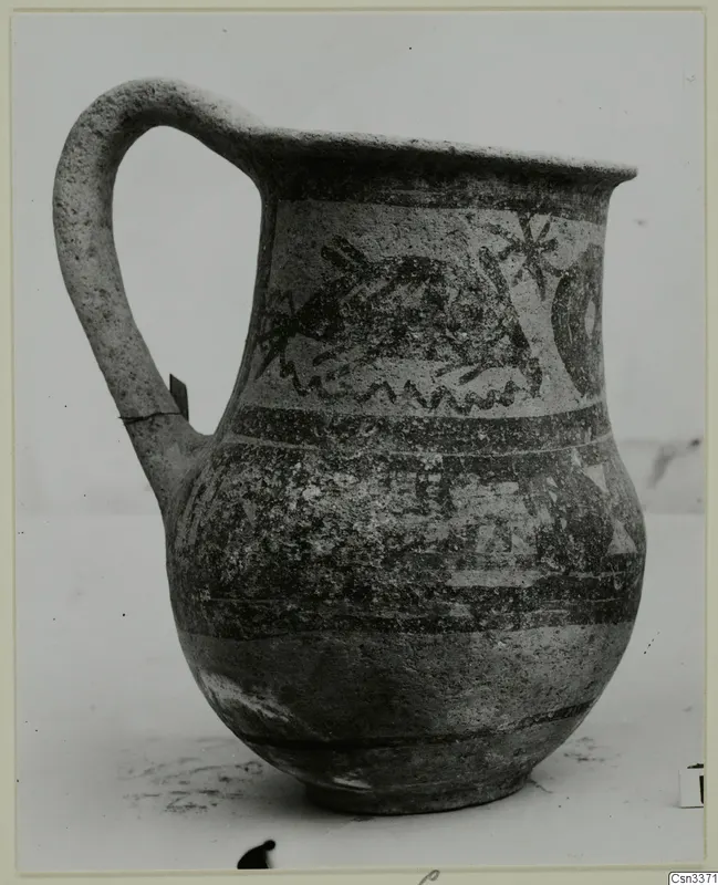 Wheel-made jug with a single handle and painted bands and motifs on its body.
