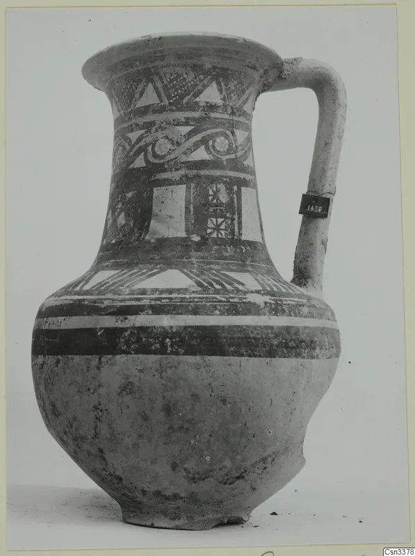 Painted jug with a curved handle, decorated with bands of triangles, scrolls and hatched panels in dark paint.