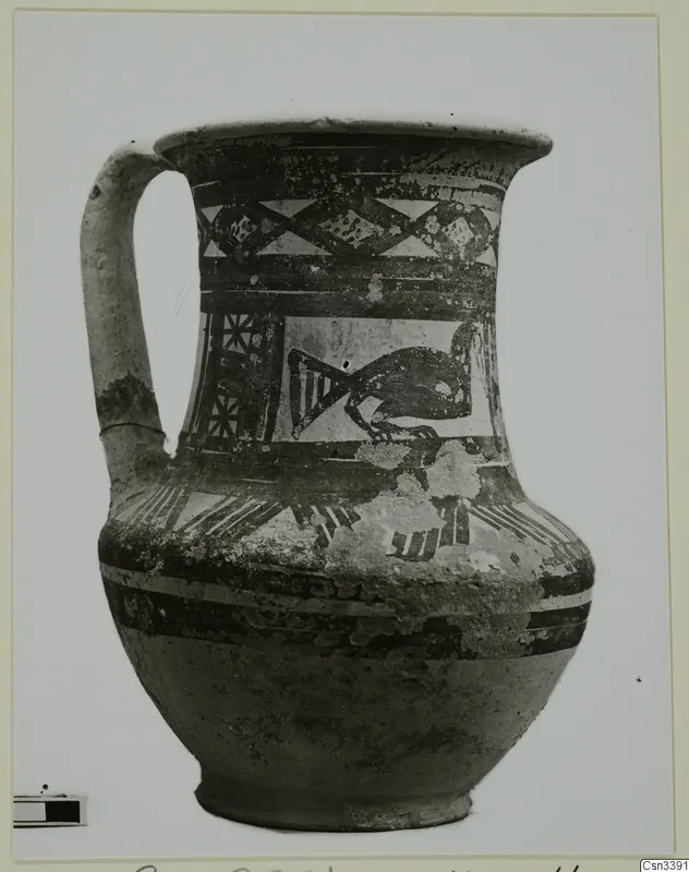 Painted jug with a single handle, bands and triangular patterns, and a dark bird-like motif on the body