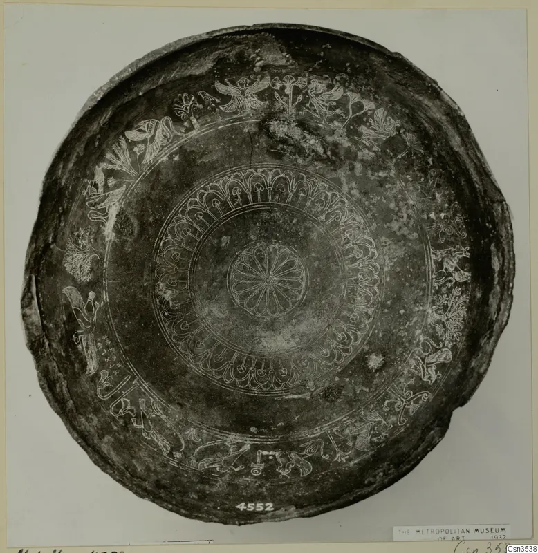 Shallow dark bowl seen from above, with engraved bands of rosettes, birds and animals around the rim