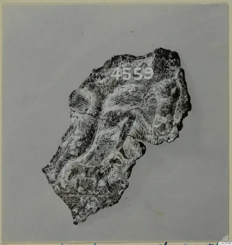Pottery sherd with circle and herringbone patterns, photographed against a grey backdrop