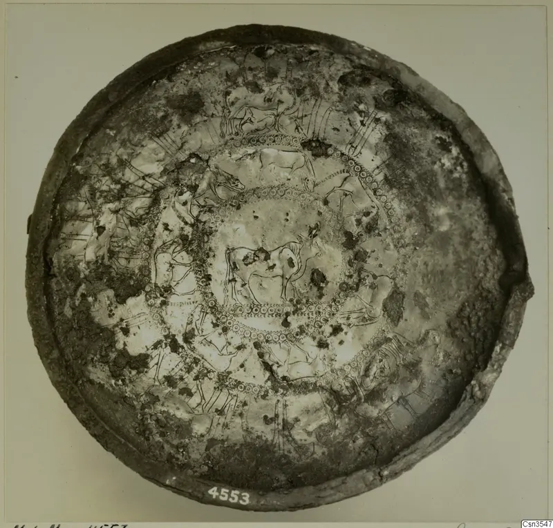 Metal bowl seen from above, its interior decorated with incised animal friezes and concentric bands of dots.