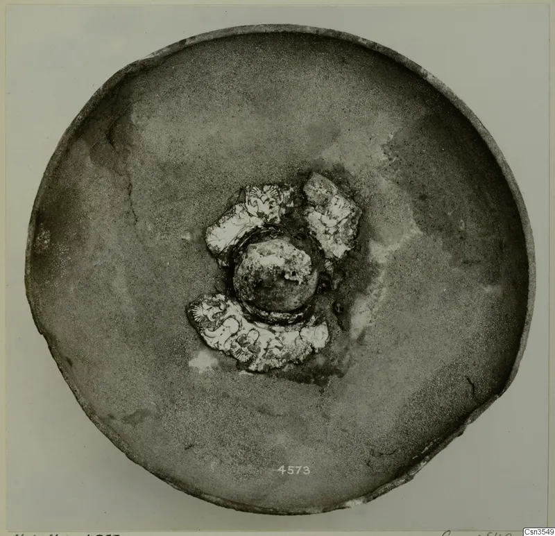 Shallow bowl seen from above, with decorated sherds and a rounded knob at its centre
