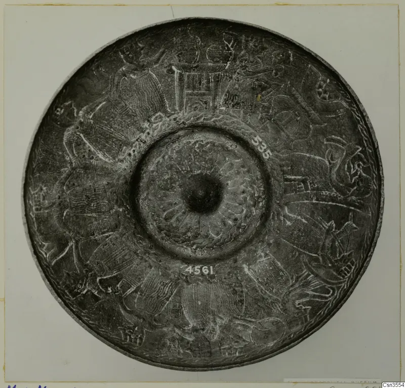 Round metal dish seen from above, with engraved figures and animal-like forms around a central boss