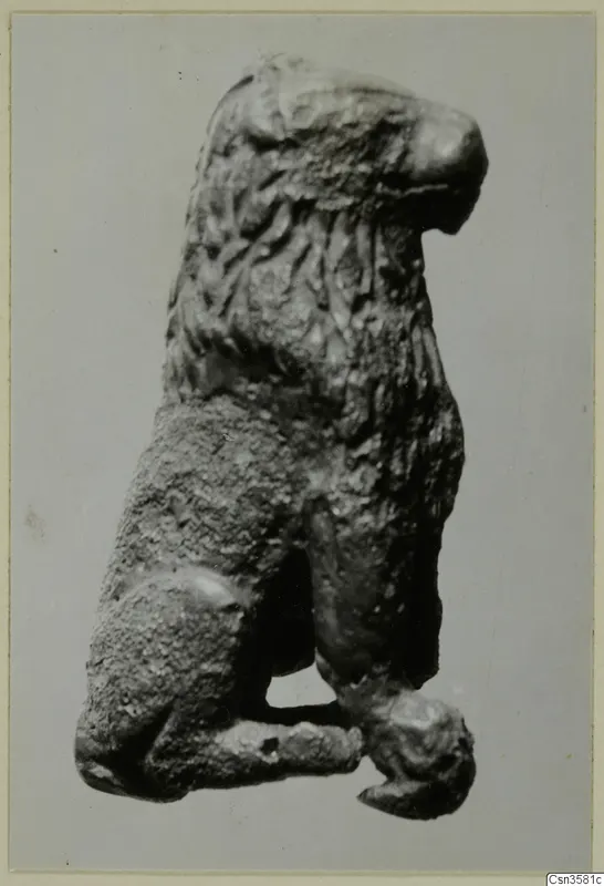 Bronze figure of a maned animal with its head raised, photographed against a plain grey background