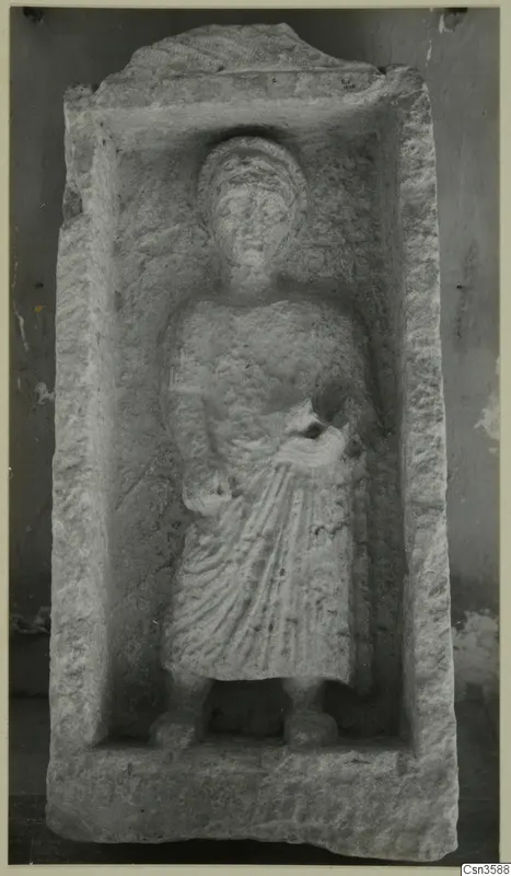 Carved stone relief of a standing figure in long drapery, set in a recessed panel, from Cyprus