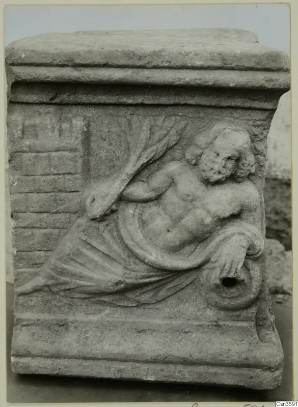 Carved relief of a reclining bearded figure on a stone block with a moulded top and base
