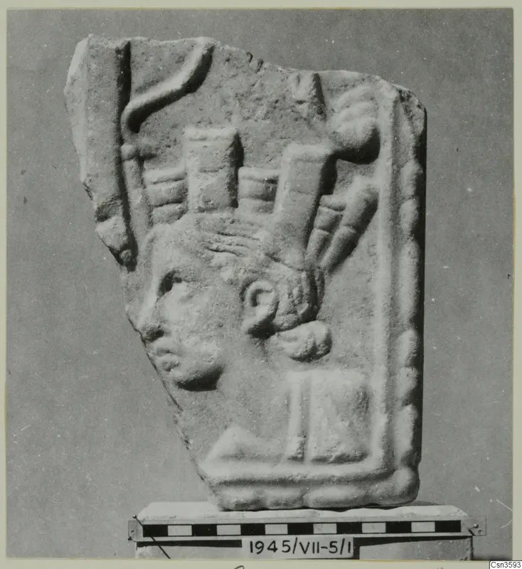 Relief fragment of a stone plaque with a head in profile facing left and a tall, upright headdress