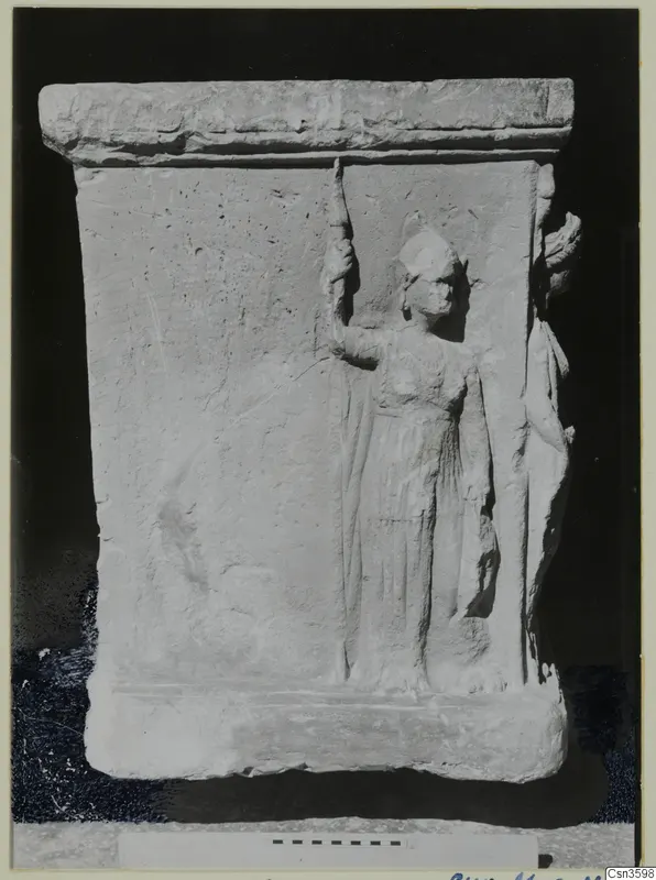 Relief on a limestone slab showing a standing figure in a long garment, raising a tall staff in one hand