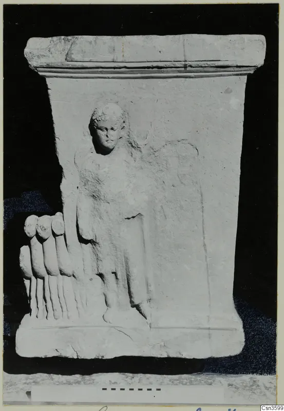 Limestone relief block with a standing figure in relief and a row of toe-like forms projecting at the left