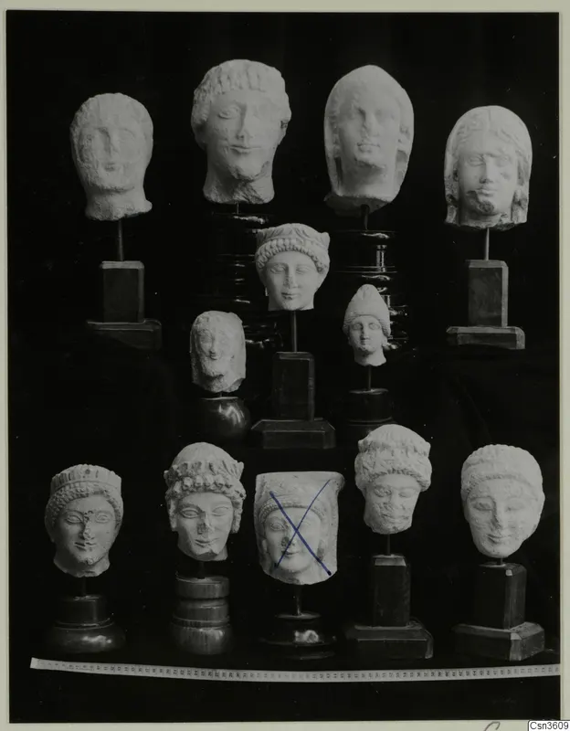 Limestone minor plastic: about a dozen carved stone heads on stands, shown in rows against a black background