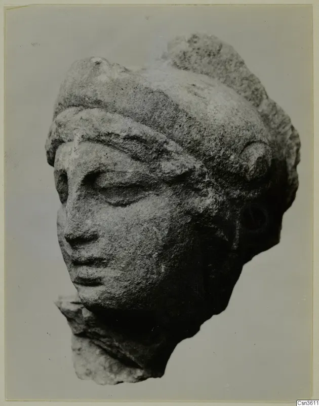 Carved marble head of a figure with a band across the brow and downcast eyes, photographed against a plain background.