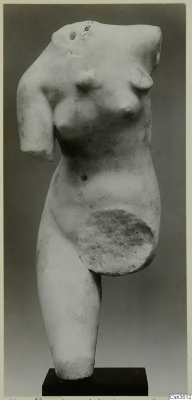 Marble sculpture of a female torso, headless and missing its arms, standing on a dark rectangular base.