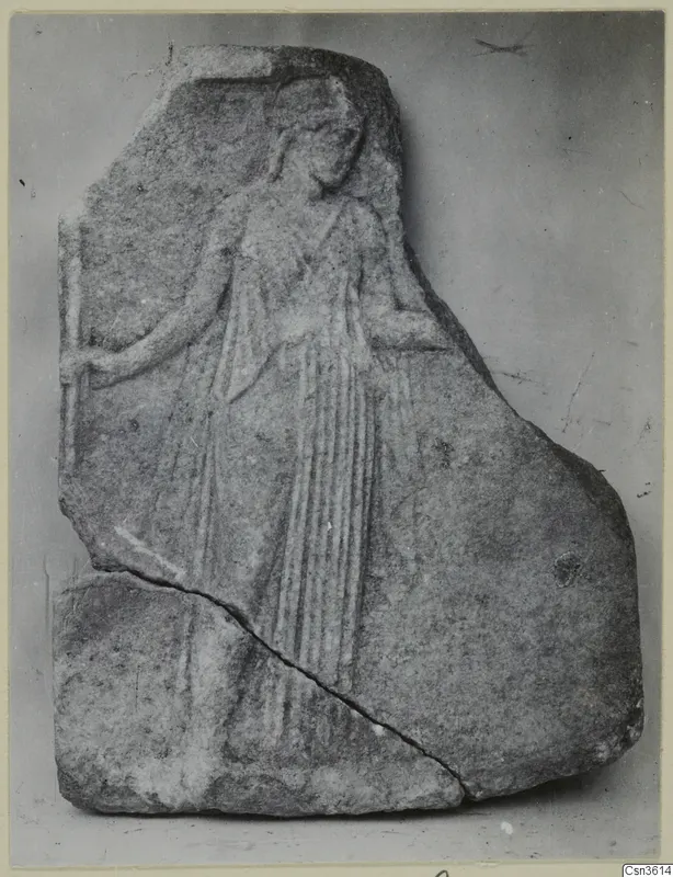 Relief fragment of a standing figure in a long pleated garment on a grey stone plaque