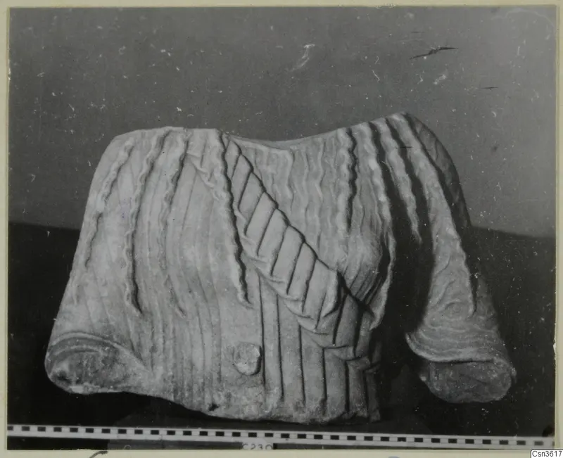 Marble sculpture fragment with carved wavy ridges and grooved bands, a rolled edge at each end, shown with a scale bar.