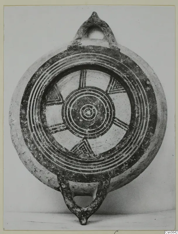 Round painted pottery vessel with two loop handles, dark concentric rings and triangular motifs on a light clay ground