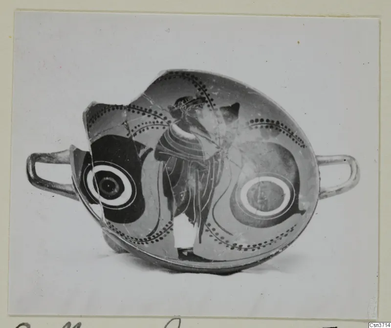 Fragmentary black-figured pottery cup with two handles, a standing figure and dotted bands