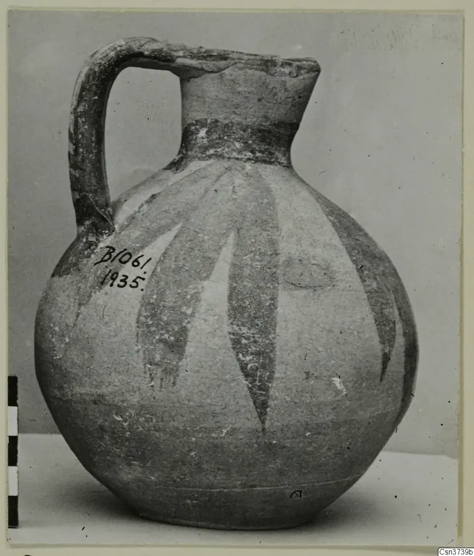 Bichrome V painted jug with a strap handle and long tapering dark bands on a pale body.