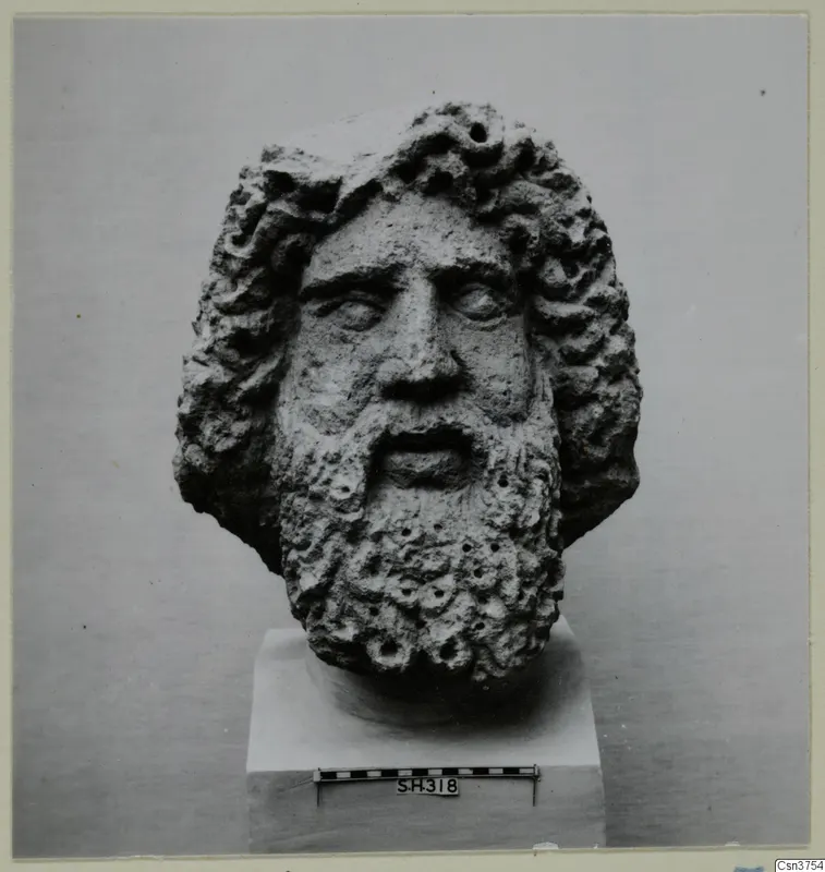 Bearded stone head from Soli on a square plinth, with a scale bar at its base