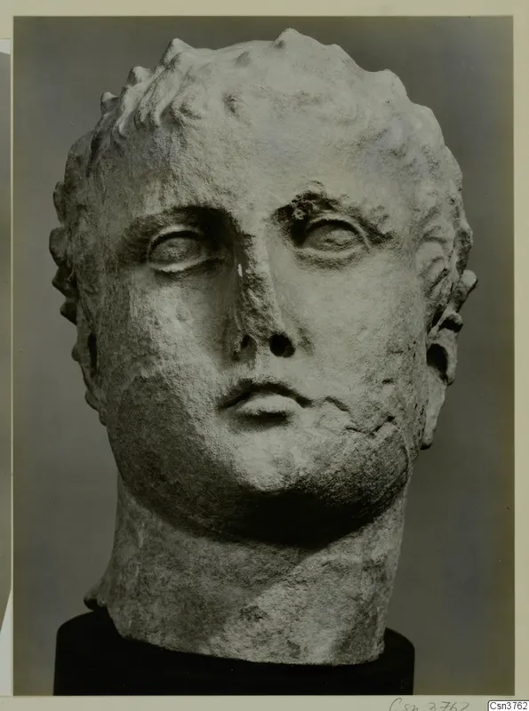 Roman sculpture: carved stone head of a man with short curled hair, shown on a dark base