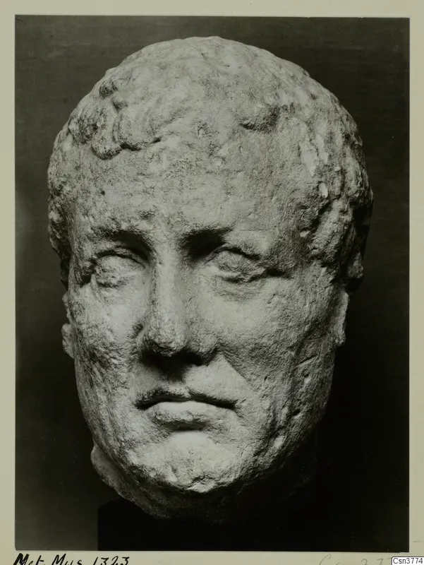 Roman stone head of a man with short curled hair, photographed against a dark background