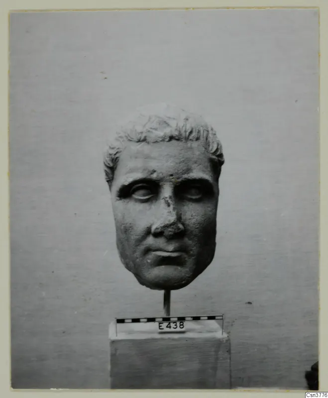 Roman sculpture: stone head of a man on a rod above a square base, with a scale bar and number label