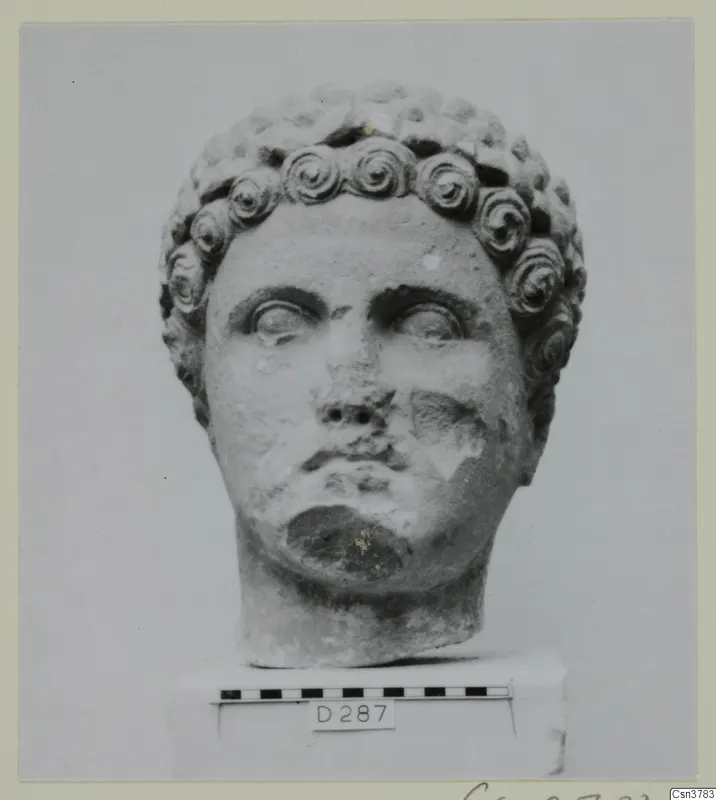 Roman sculpture: carved stone head with curled hair, shown on a base beside a scale bar.