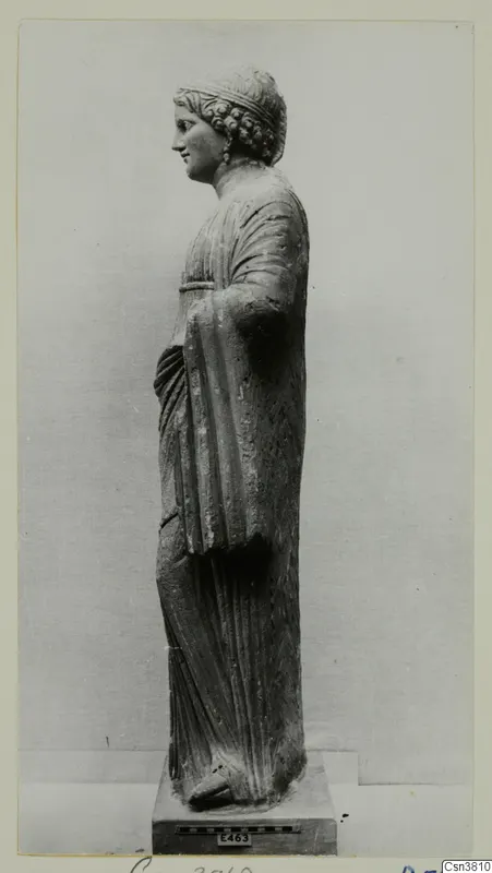 Draped stone statue of a standing figure, seen in profile on a square base.