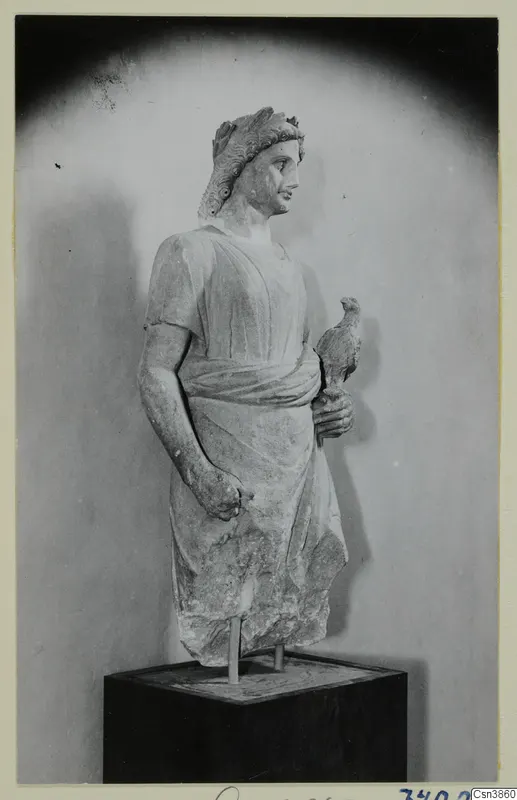 Stone statue of a standing figure with a wreath in its hair, holding a small bird