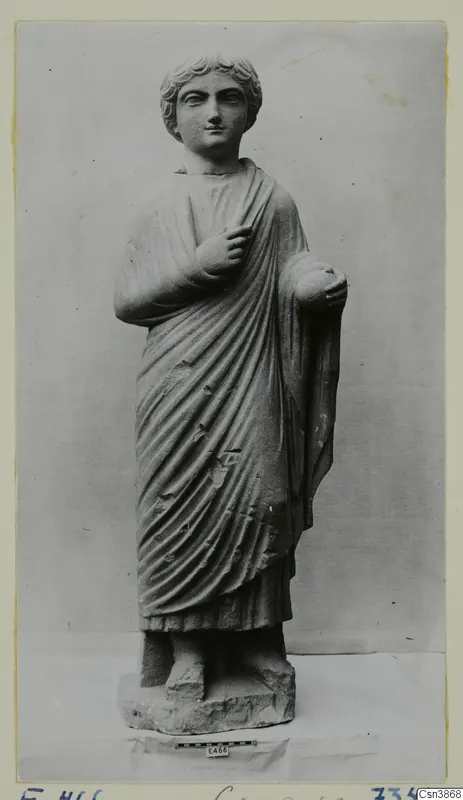 Standing draped stone statue of a young figure with short curled hair, mounted on a rectangular base.