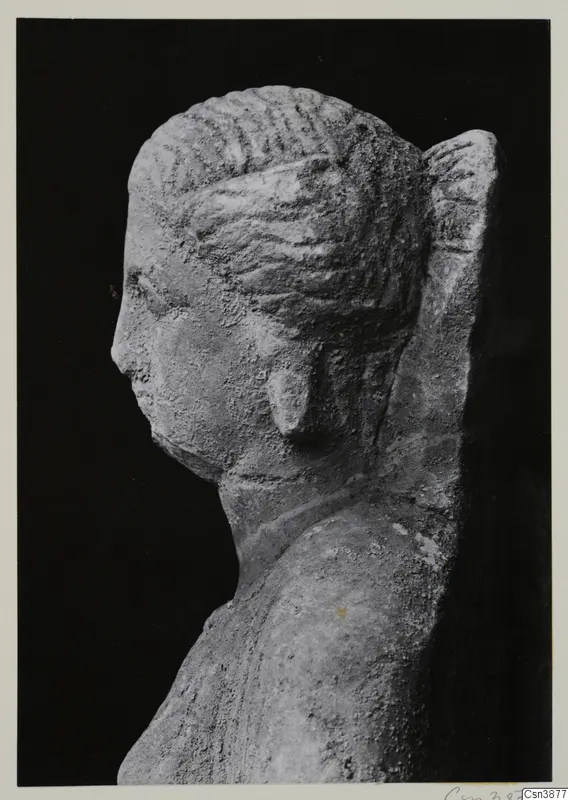 Stone sculpture of a head and upper body in left profile, set against a black background