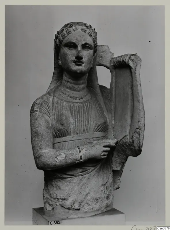 Stone statue of a female figure with curled hair and a veil, holding a lyre-shaped instrument beside her shoulder