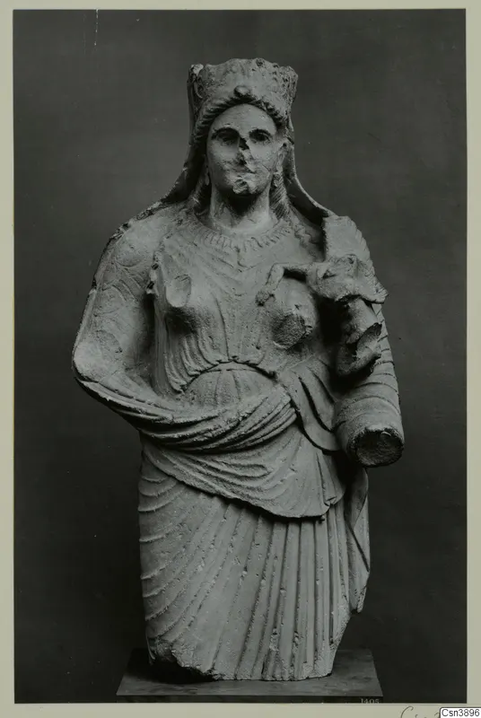 Stone statue of a female figure with a tall headdress and draped garment, holding a cylindrical object against her side