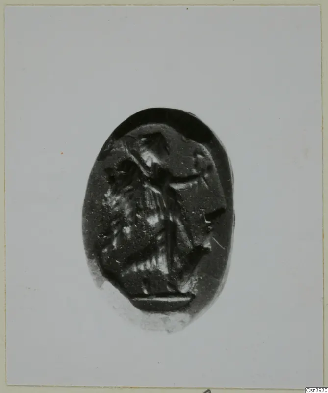 Oval dark stone gem engraved with a figure in profile facing right, shown on a light card