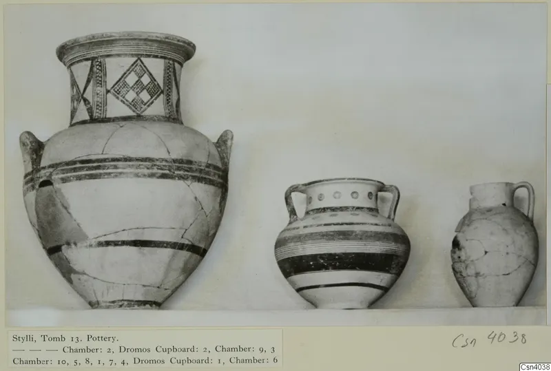 Three painted pottery vessels from Stylli Tomb 13 standing in a row on a shelf.
