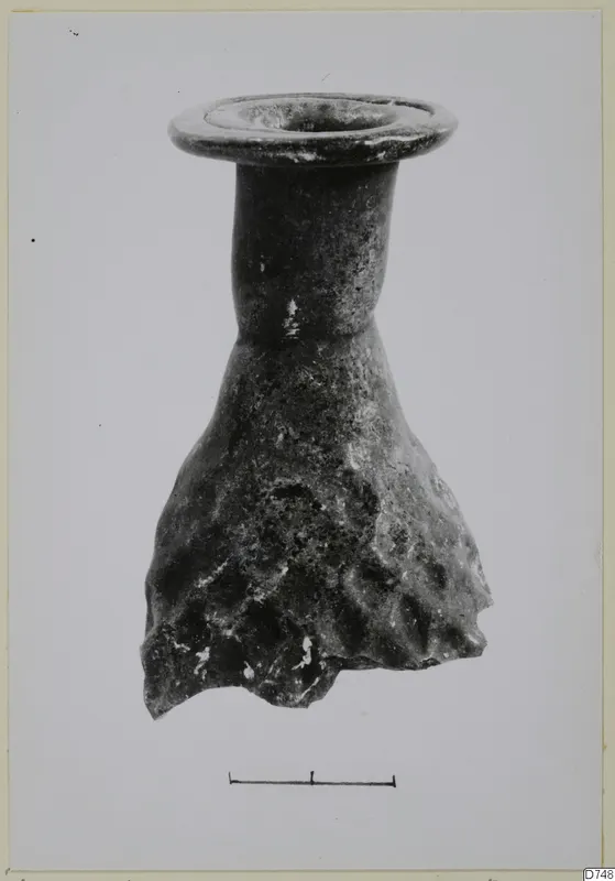 Blown glass vessel with a flared rim, narrow neck and lower body with a dimpled, weathered surface
