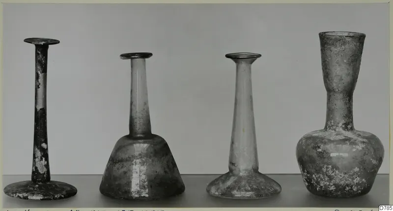 Four blown glass vases standing in a row, each with a narrow neck and flared rim