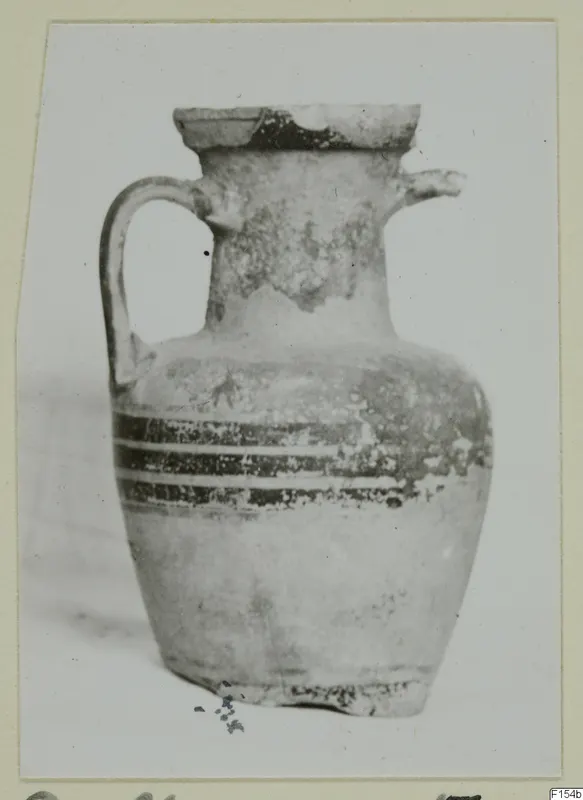 Pottery jug with a strap handle, a small spout and dark bands around the upper body