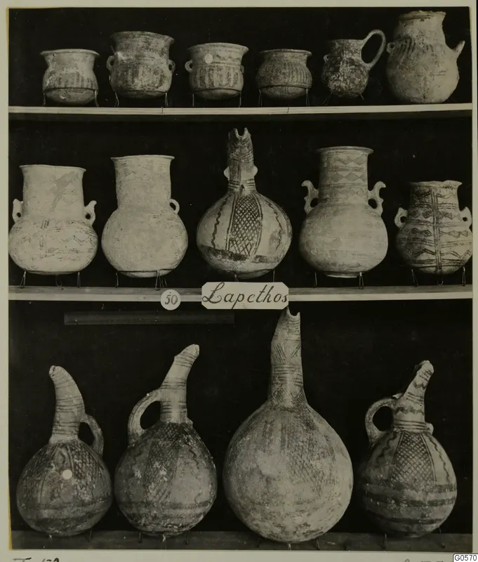 Pottery vessels from Lapithos Markides Tomb 50 arranged on three shelves against a dark background.