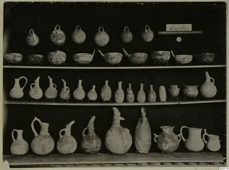 Shelves of pottery vessels from Lapithos Markides, T.49: loop-handled jugs, open bowls and juglets on stands.