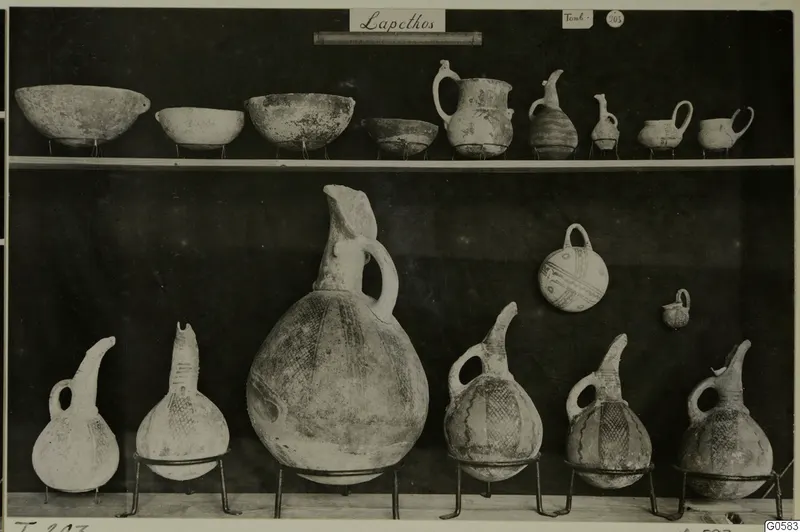 Pottery bowls and jugs from Lapithos Markides, T.203, arranged in two rows against a dark background.