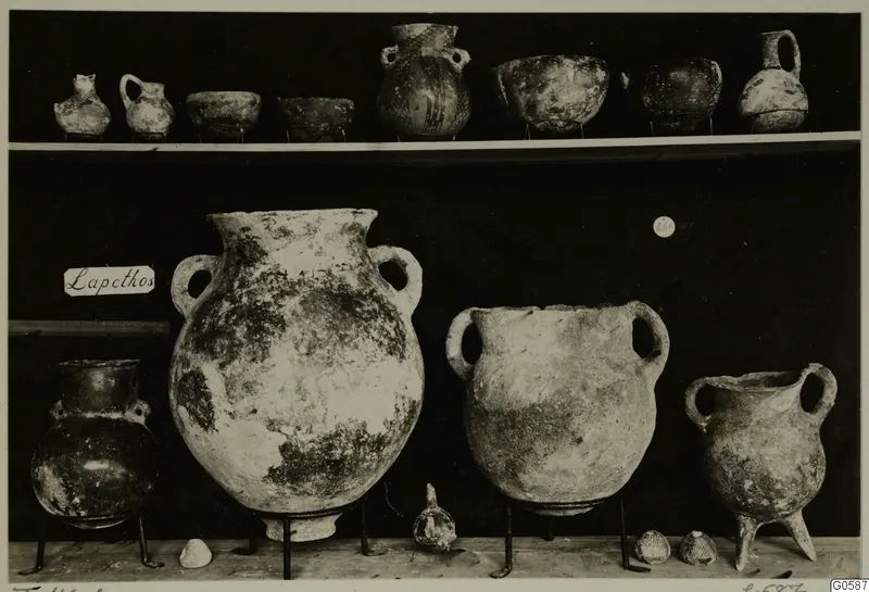 Jugs, bowls and large two-handled jars displayed on two shelves, labelled Lapithos, from Markides T.46 A.