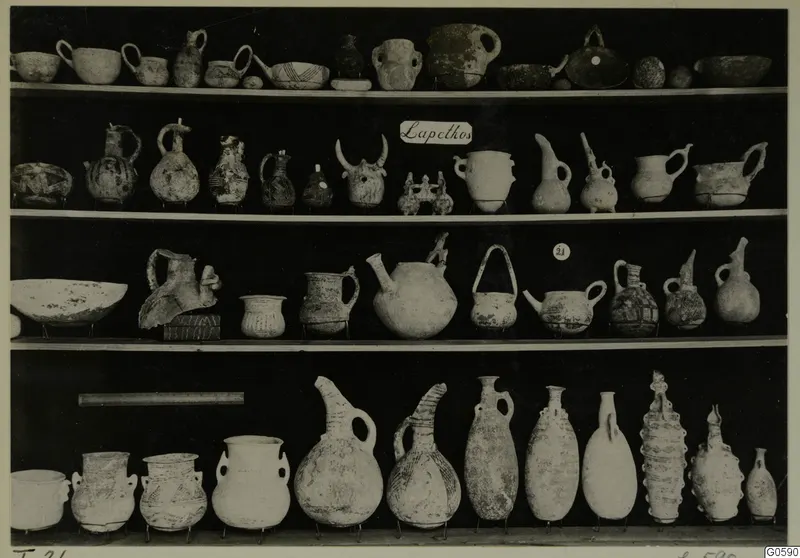 Rows of pottery jugs, juglets and bowls displayed on shelves, from Lapithos T.21