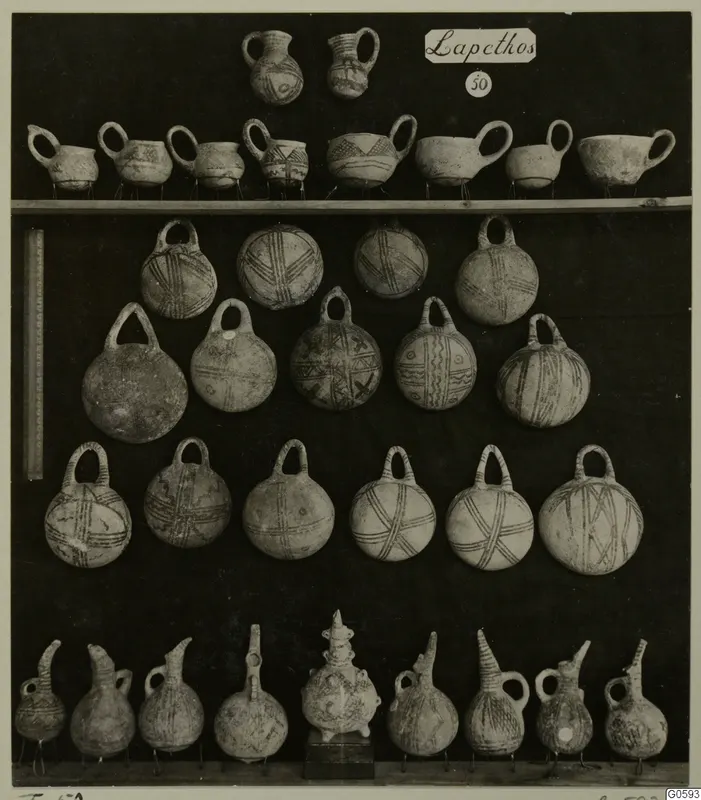 Jugs, cups, bowls and round flasks from Lapithos, T.50, arranged in rows on a dark board