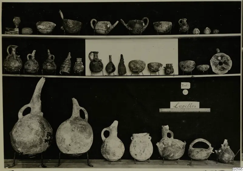 Jugs, bowls and flasks from Lapithos Markides, tomb 201, set out on three shelves against a black background