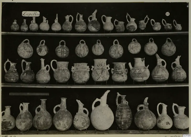 Jugs and juglets from Lapithos Markides T.29, arranged on three shelves against a dark background.