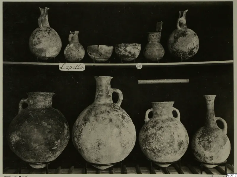 Pots and bowls from Lapithos Markides T.205, arranged on two shelves against a dark background