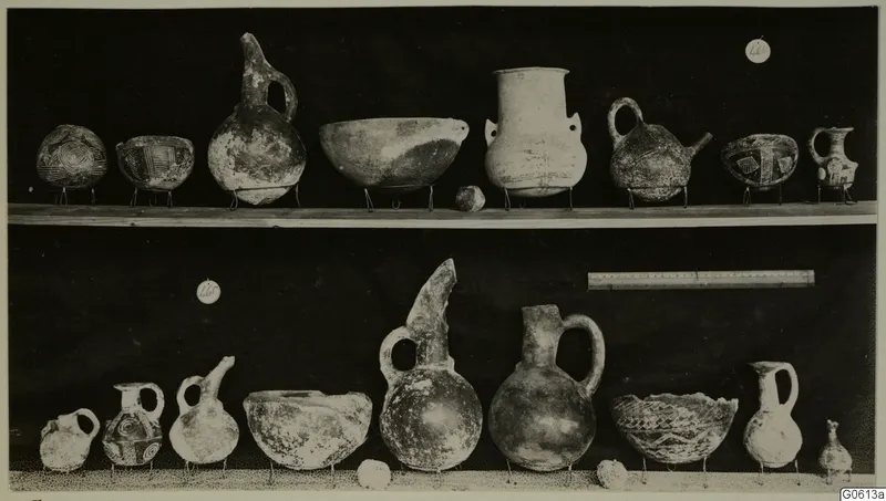 Pottery vessels from Lapithos Markides T.46B-e, shown in two rows on small wire stands against a dark background